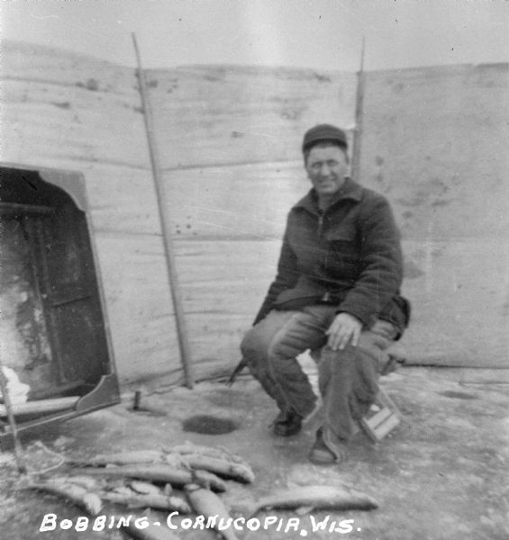 An ice fishermen sitting in a shelter bobbing for fish on Lake Superior near Cornucopia.