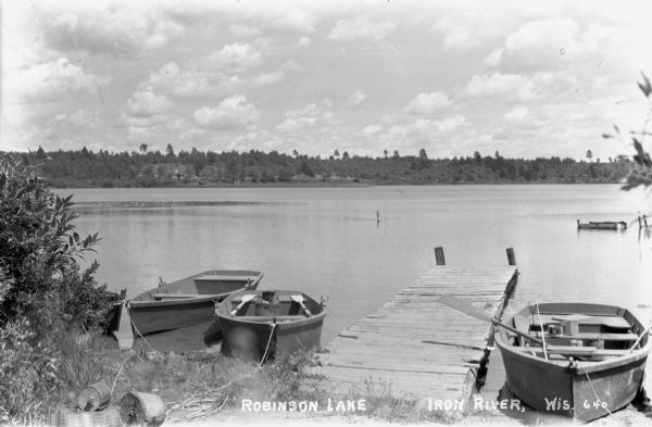 View from shoreline of wooden row boats near pier on Robinson Lake.