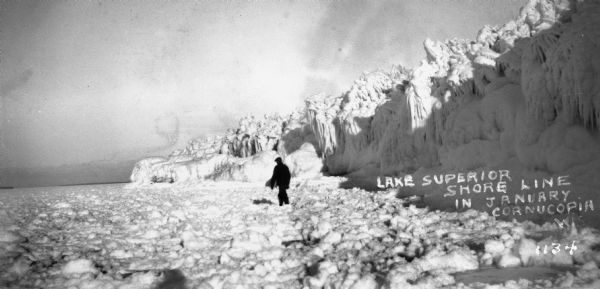 View of a man walking on the ice near the Lake Superior shoreline.