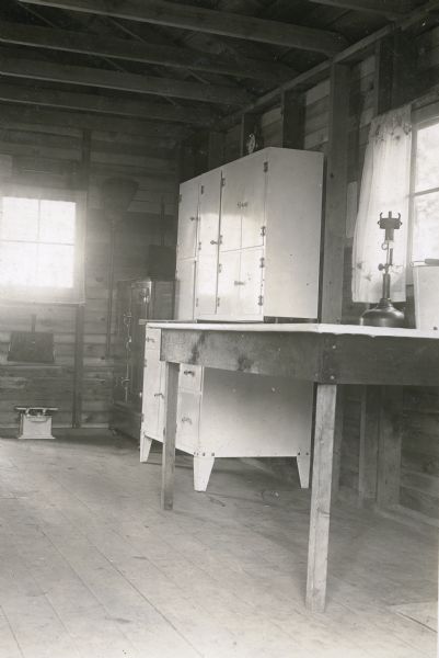 Interior view of the kitchen area showing a table, cupboards, ice box, broom, and windows, in a cottage at Nature Lovers Paradise on Jackson Lake near Grand View.<p>Located within the Chequamegon National Forest, Jackson Lake is a 142 acre drainage lake with a navigable outlet channel to Namakagon Lake – which is a 3,227 acre drainage lake at the headwaters of the Namakagon River in Bayfield County.</p>