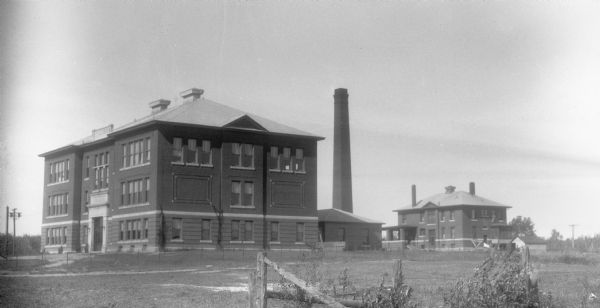 View of the Ondossagon Public School building. The three-story brick structure was built in 1917. In the background are other brick additions and another three-story brick building.