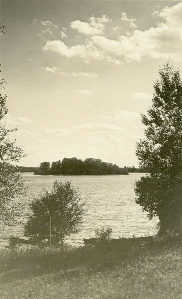 View taken from shore looking out over a lake at an island with trees and the opposite shoreline. Text describing this photograph says, "scenes looking from our cottages" and "Lake Namakagon."<p>Located within the Chequamegon National Forest, Jackson Lake is a 142-acre drainage lake with a navigable outlet channel to Namakagon Lake – which is a 3,227 acre drainage lake at the headwaters of the Namakagon River in Bayfield County, Wisconsin.</p>
