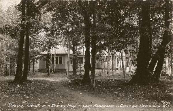 View of the Bobynn Tavern and Dining Hall on Lake Namakagon near Cable and Grand View, Wisconsin. The single-story building is down a path through the trees.