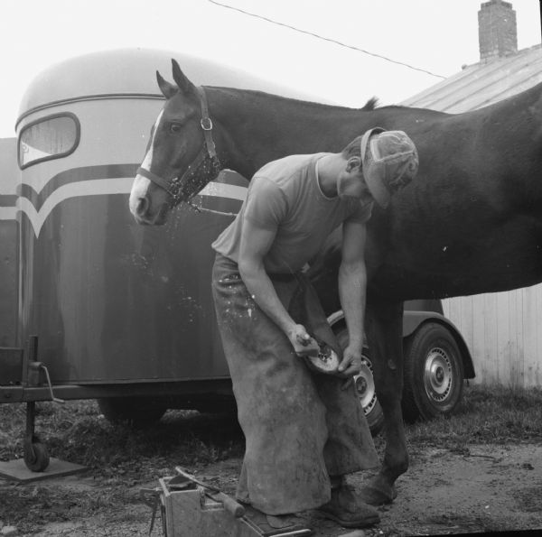 Jim Rupple prepares a horse's hoof before shoeing the horse.