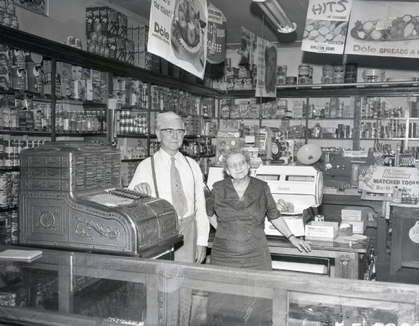A man and woman stand behind the service counter at a drugstore.
