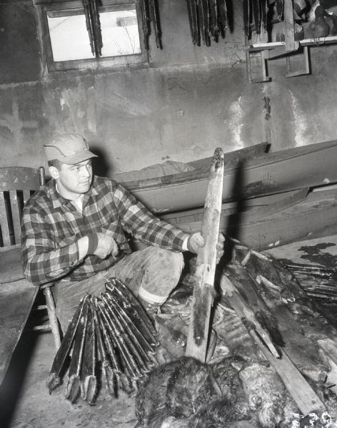 A man holds a wood stretcher/fleshing beam near his game.