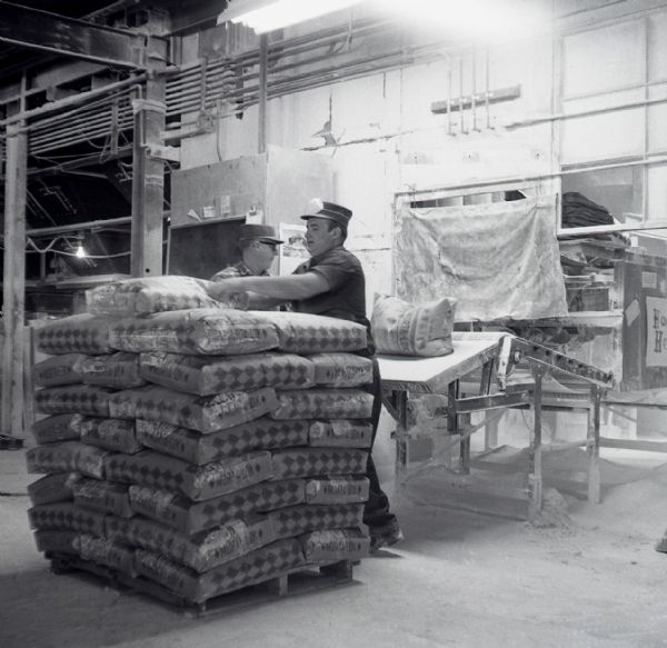 Worker stack bags of lime onto a palette.