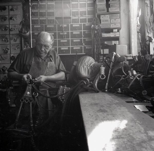 A shoemaker constructs a harness.