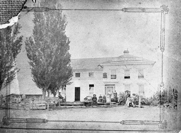 Copy photograph of a group portrait outside the Waupaca House general store.