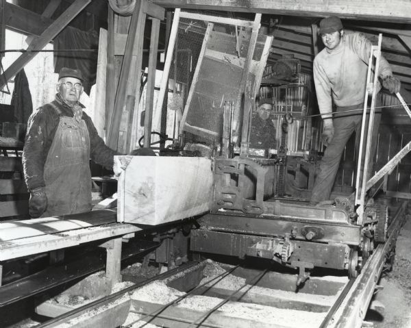 Paul Timm, Arno Timm and Stephen Timm work together sawing a log, which has full 16 foot boards and is 20 feet long.