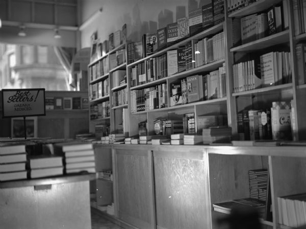 Inside of the People's Bookstore. Bookshelves, counters and cabinets of leftist books. Some titles are visible including <i>Battle for Asia</i>, <i>Women in the Soviet East</i> and <i>History of the American Revolution</i>.