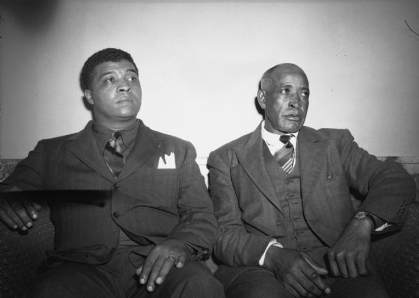 Gene Turman, Local 1533, Beloit (younger) and M.W. Henderson, Local 2763, Galesburg, Illinois, sit on a couch at the United Steelworkers of American District 32 convention. The men wear suits and are looking to the right.