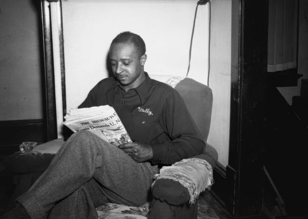 Isaiah Pyant, C.I.O. member, sitting in an armchair in his home reading the newspaper.