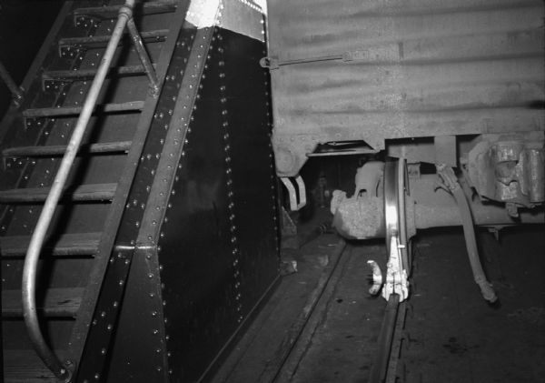 View of a metal stairway and a train car wheel and undercarriage. Part of a series on working conditions aboard Lake Michigan railroad car ferries. Ferry workers belonged to the National Maritime Union (NMU).