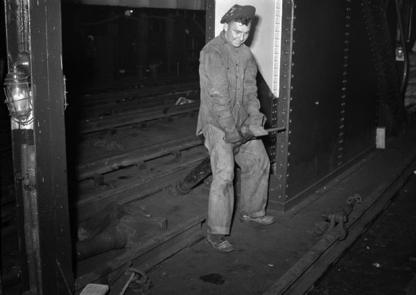 Young worker operates a large lever on railroad tracks. Part of a series on working conditions aboard Lake Michigan railroad car ferries. Ferry workers belonged to the National Maritime Union (NMU).