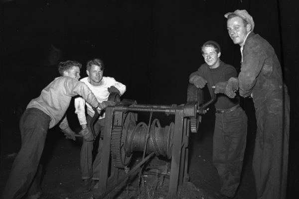 Four workers operating an "ancient" winch. Part of a series on working conditions aboard Lake Michigan railroad car ferries. Ferry workers belonged to the National Maritime Union (NMU).