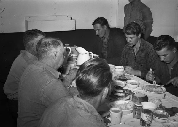 Workers eating dinner. Part of a series on working conditions aboard Lake Michigan railroad car ferries. Ferry workers belonged to the National Maritime Union (NMU).