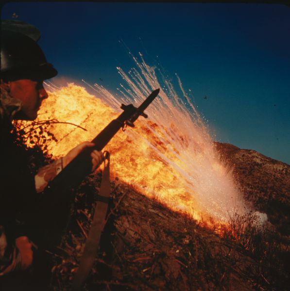 Marine and bayonet silhouetted in a fiery blast of napalm.  Taken during a napalm testing maneuver at Camp Pendleton.