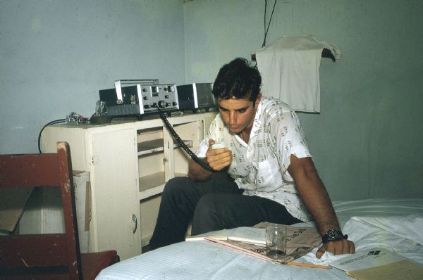 A member of the anti-Castro group Commandos L sitting on a bed testing a new radio transmitter-receiver.