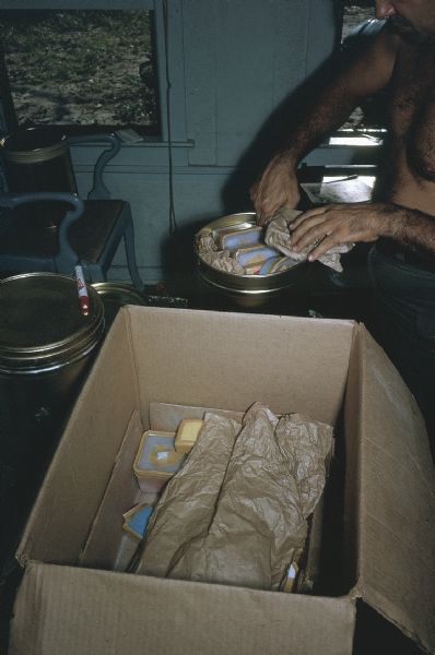 Member of the anti-Castro group Commandos L packing explosives into a large can.  A box containing the loose explosive pucks is in the foreground.