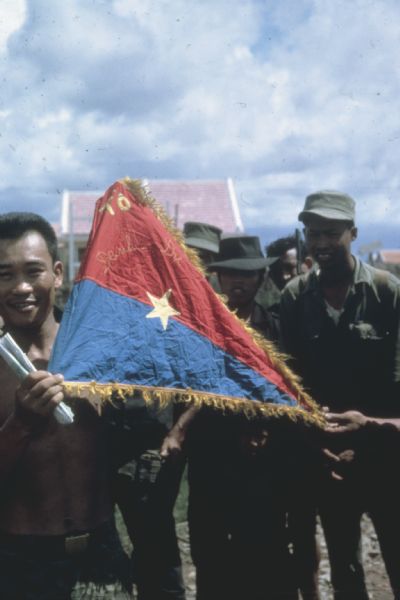 A group of Vietnamese soldiers display a South Vietnamese flag they captured in combat.