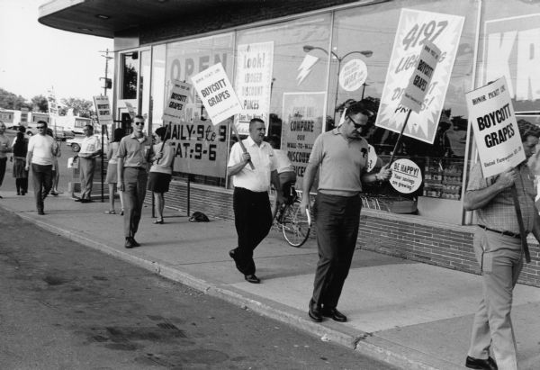 Picketers in front of Kroger supermarket in Milwaukee carrying United Farmworkers (UFW)/AFL-CIO signs that read, "Boycott Grapes" to support the grape boycott. Grape boycotts in Wisconsin were organized by the local farm-worker labor union, Obreros Unidos (United Workers), an independent farm worker labor union effort in the 1960s.
<p></p>Manifestantes por el boicot de uvas en Milwaukee
<p></p>Manifestantes enfrente del supermercado Kroger en Milwaukee sosteniendo letreros de United Farmworkers (UFW)/AFL-CIO que dicen "Boicotea las uvas" ("Boycott Grapes") para apoyar el boicot. Los boicots de uva en Wisconsin fueron organizados por Obreros Unidos, un esfuerzo independiente del sindicato de trabajadores agrícolas durante los años 1960.

