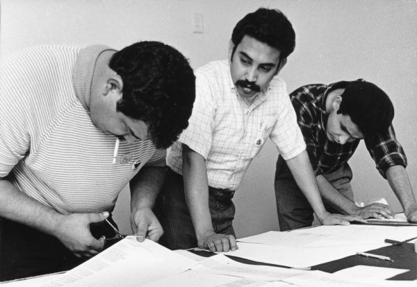 Roberto Hernandez (left) and Esequiel Guzman (center) work on the layout of "La Guardia" newspaper. The underground bilingual newspaper was published in Spanish and English from 1969-1982 in Milwaukee.<p>The newspaper was created during the time of the labor movement led by Chicano laborers' union Obreros Unidos (United Workers) to improve migrant workers rights.<p>Organizadores del periódico "La Guardia"<p>Roberto Hernández (a la izquierda) y Esequiel Guzmán (al centro) trabajan en la composición del periódico "La Guardia." El periódico clandestino era publicado en español e inglés entre los años 1969-1982 en Milwaukee.<p>El periódico fue creado durante el esfuerzo laboral dirigido por trabajadores chicanos del sindicato Obreros Unidos, para mejorar los derechos de los trabajadores emigrantes.</p>