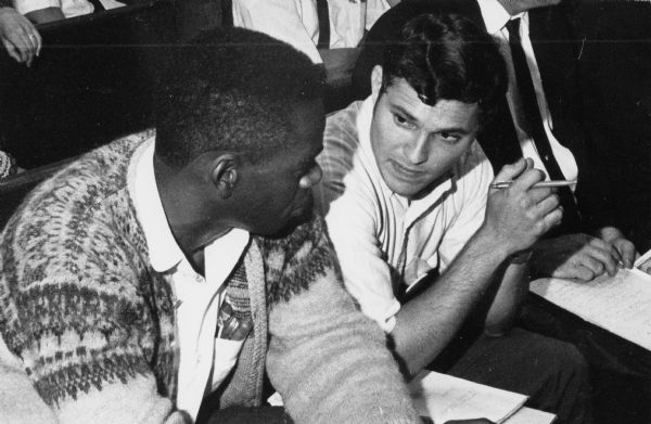 On the left, Bill Smith, administrative assistant for Obreros Unidos (United Workers), the Wisconsin migrant farm workers' union. On the right, Mark Erenberg, an economist. They are at a hearing. Both men advocated for better working conditions for migrant farm workers.<p>Strikes in Wisconsin were organized by the Obreros Unidos, an independent farm worker labor union effort in the 1960s.</p>