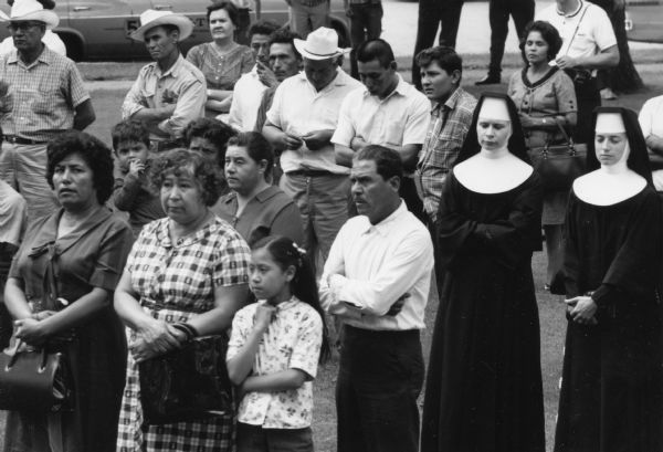 A crowd of migrant workers, children and nuns attending at pre-march rally listening to Jesus Salas, union leader, speak in front of the Waushara County Courthouse. Marchers of Obreros Unidos (United Workers) will begin the march from Wautoma. They walked to Madison on Highway 21 to petition lawmakers to hold farms and food industry corporations accountable for better working conditions for migrant farm workers.<p>This photograph is a part of Wisconsin-native David Giffey's series "Struggle for Justice," images from the migrant farm worker struggle including an independent oganizing effort in Wisconsin and
the nationwide grape boycott movement started by Cesar Chavez of United Farm Workers during the 1960s and 1970s.<p>Pre-marcha de la manifestación en el tribunal del condado de Waushara<p><Una multitud de trabajadores emigrantes, niños, y monjas están acudiendo a una marcha antes de la manifestación para escuchar a Jesús Salas, un líder de sindicato, que habla enfrente del tribunal o Waushara County Courthouse. Manifestantes de Obreros Unidos empezaron la marcha desde Wautoma. Ellos caminaron hacia Madison en la carretera Highway 21 para peticionar a los legisladores estatales que mantengan responsables a los agricultores y corporaciones en la industria de comida para el mejoramiento de las condiciones de los trabajadores agrícolas emigrantes. Esta fotografía es parte de la serie "Lucha por la Justicia" tomada por David Giffey, originario de Wisconsin, las imágenes muestran la lucha de los trabajadores agrícolas emigrantes incluyendo un esfuerzo independiente organizado en Wisconsin y el movimiento nacional del boicot de uvas empezado por Cesar Chávez de la unión de campesinos o United Farm Workers durante los años 1960 y 1970.</p>