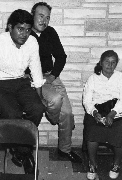 Jesus Salas, seated at left, is with workers at one of six Industrial Hearings in  Wisconsin. The Waushara County Courthouse hearing discussed the issue of paying minimum wages to migrant farm workers.<p>Strikes, rallies and marches in Wisconsin were organized by the Obreros Unidos, an independent farm worker labor union effort in the 1960s.<p>Jesús Salas en el público durante la audiencia de la Comisión Industrial<p>Jesús Salas, sentado a la izquierda, está con trabajadores en una de las seis Audiencias Industriales en Wisconsin. La audiencia del tribunal del condado o Waushara County Courthouse discutió la cuestión de pagar un sueldo mínimo a los trabajadores agrícolas emigrantes. Las huelgas, manifestaciones, y marchas en Wisconsin fueron organizadas por Obreros Unidos, un esfuerzo independiente del sindicato de trabajadores agrícolas durante los años 1960.</p>