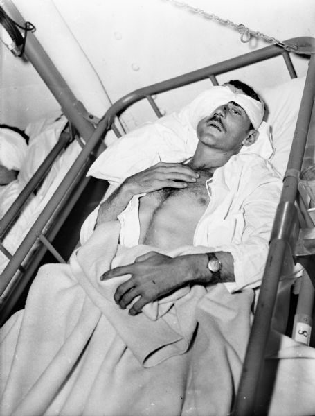 A badly wounded Sergent Frank W. Mrocykowski resting aboard the USS <I>Samaritan</I>. His head and eye are bandaged.