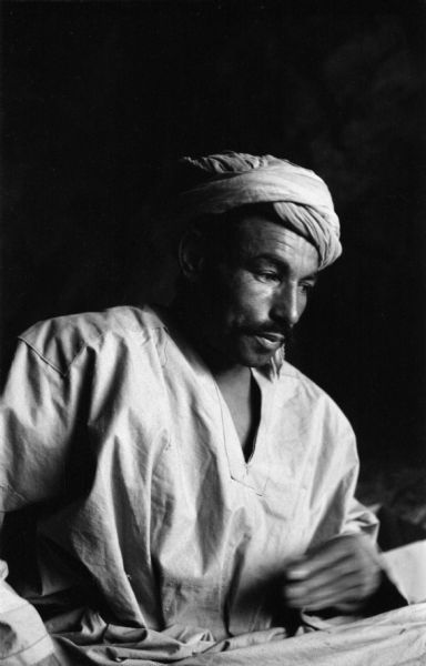An Algerian member of the National Liberation Front posing for a portrait inside a cave, wearing a turban.