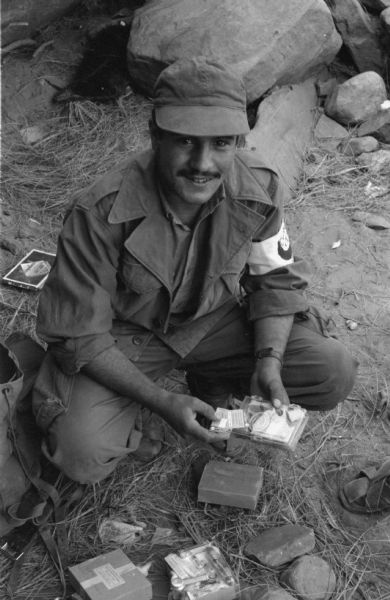 An Algerian Red Crescent (Red Cross equivalent) worker poses for a photograph while gathering supplies for tending to wounds. He wears a Red Crescent arm band to identify himself.