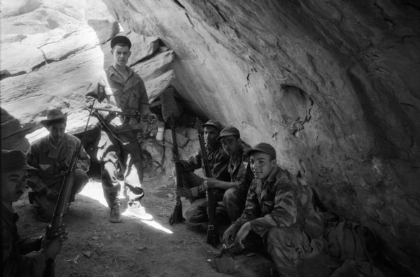 A group of National Liberation Front Members posing inside a cave with their rifles.