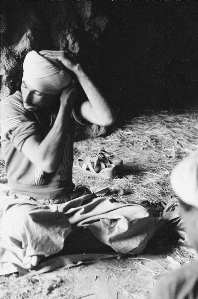 An Algerian member of the National Liberation Front adjusting his turban in a cave.