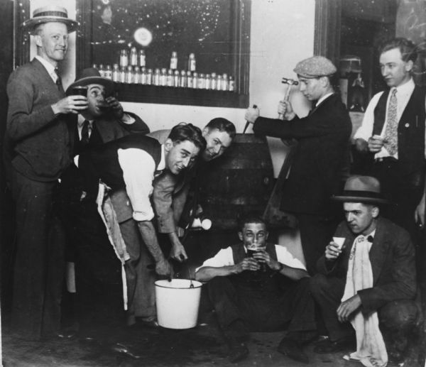 A keg of Prohibition Era beer in the darkroom of the "Milwaukee Sentinel" being enjoyed by newspapermen: (left to right) Red Thisted, Eddie Oroth, Guy Helsm, Otto Brinkman, Ira Bickhart, Alvin Steinkopf, and sitting, Benny Benfer and Mr. Carr.