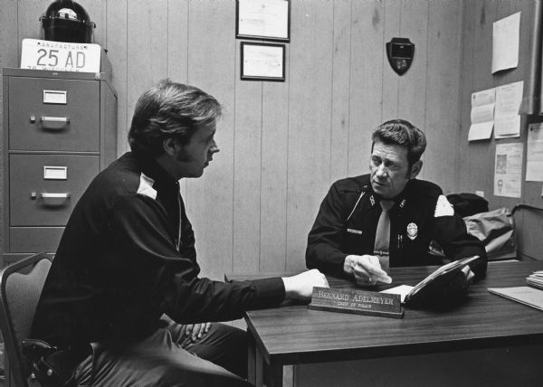 "Police Chief Bernie Adelmeyer explains duties to rookie officer, Mike Mansfield. Adelmeyer has been chief for seven years, but had previous experience in law enforcement."