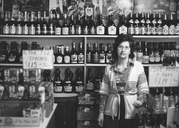 "Mrs. Bruce Dunbar poses amid shelves of fine wine and liquor at Dunbar's Inn."