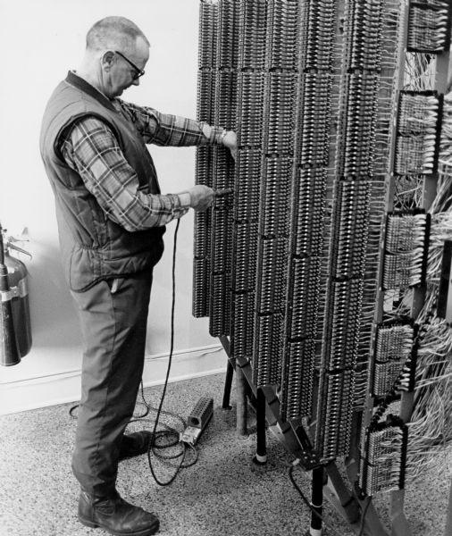 "Theresa telephone office. Thirty-year employee, Donald Lawrence, solders on the main frame of the central office switching equipment."