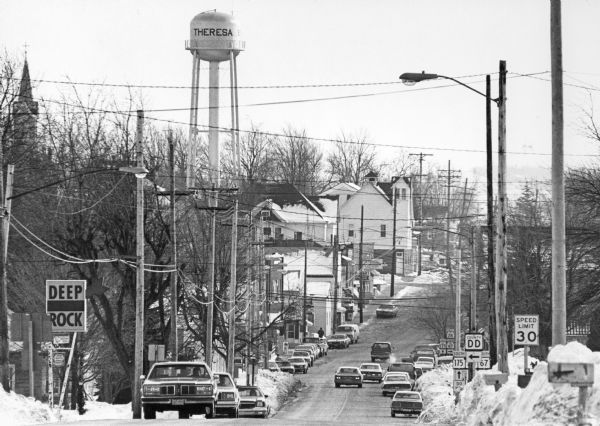 View of Theresa main street including water tower. "The telephoto lens compresses the distance between telephone and light poles."