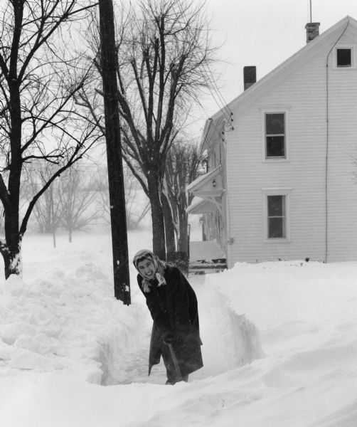 Winter scene of Shirley Widmer, the photographer's wife, digging out a snow-covered sidewalk.  Caption: "Shirley Widmer digs out after a big snowstorm."