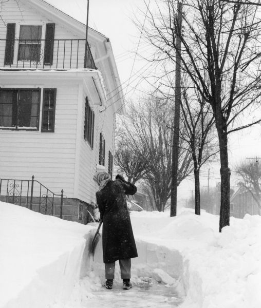 Winter scene with Shirley Widmer, the photographer's wife, shoveling snow after a big snowstorm.
