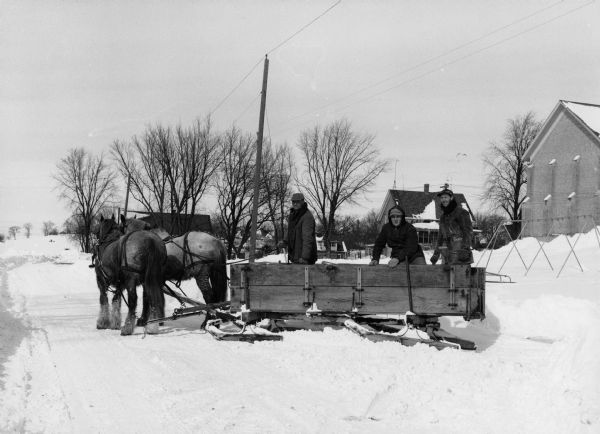 "Erhard Luhn, Richard Sigler, & Howard Greiner are bringing milk to Widmer Cheese Factory in a horse-drawn sleigh."