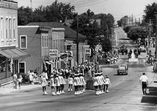 "A roller skating troupe rolls down Milwaukee Street."