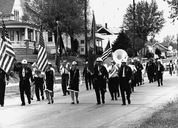 View of a marching band leading a parade down a residential street.