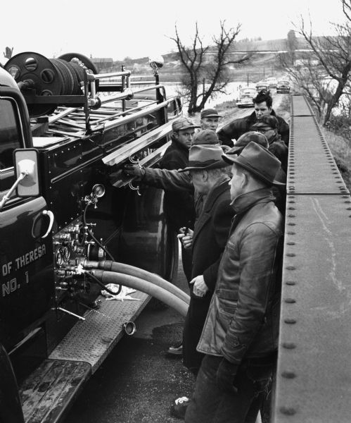 "Theresa firemen drill on the bridge on North Pole Rd. The camera faces north. Some of the firemen are Les Beck, Andrew Schnitzler, Armand Zimmel, & Les Zimmel."