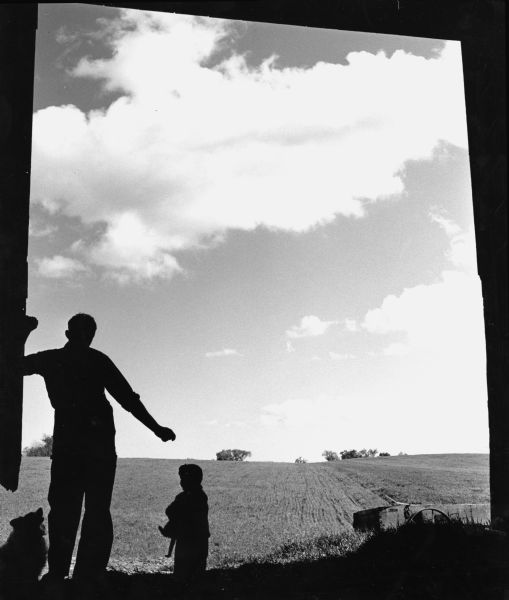 "Jim Dobbe & his daughter are silhouetted in the doors of their barn.  This is the site of Schnitzler's River View Hills mobile home park."