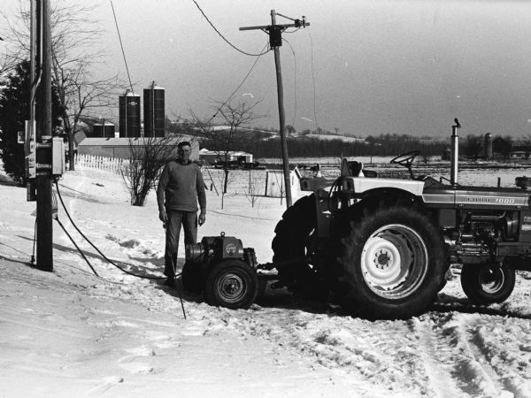 "As a result of the storm some farms did not have electricity for five days. A generator was shared by many farmers and was moved from farm to farm so that cows could be milked. Vern Steger is shown operating the generator."