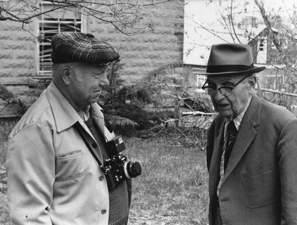 "Mayville photographer, Edgar Mueller, confers with 'Corny' Weber. Mr. Weber took some early photos in the village. Some of his glass plate negatives are in possession of Theresa Historical Society members."