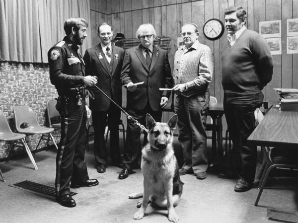 "Police officer, Bill Poellot, shows off his police dog to Cliff Dogs, Neil Coulter, Gordon Loehrke, and Lynn Zimmel."